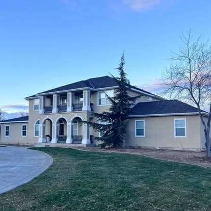 Elegant two-story home with arched balconies, green lawn, and clear sky in the background.