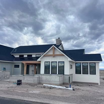 Modern single-family home under construction with large windows and gray clouds overhead.